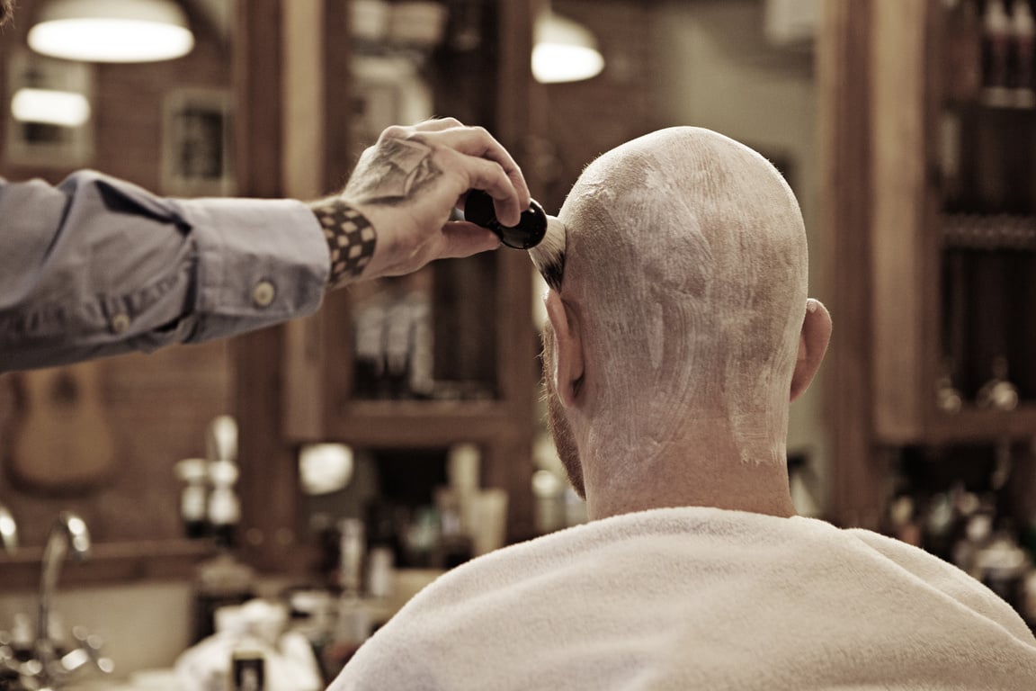 Tattooed barber with a bearded bald male client